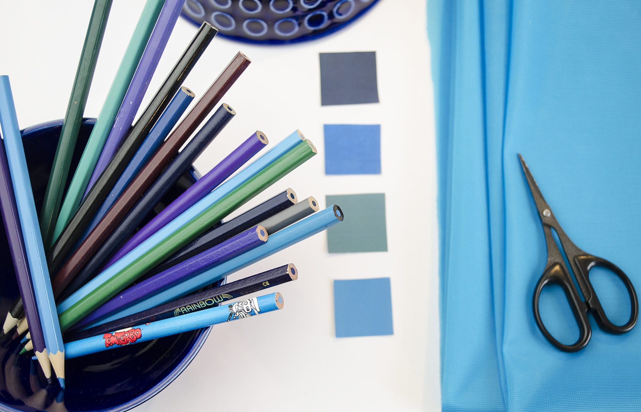 Moodboard Textildesign Assemblage mit Bunstiften, Farbschema, Farbkarten mit Dederon, Schere und blauer Schüssel